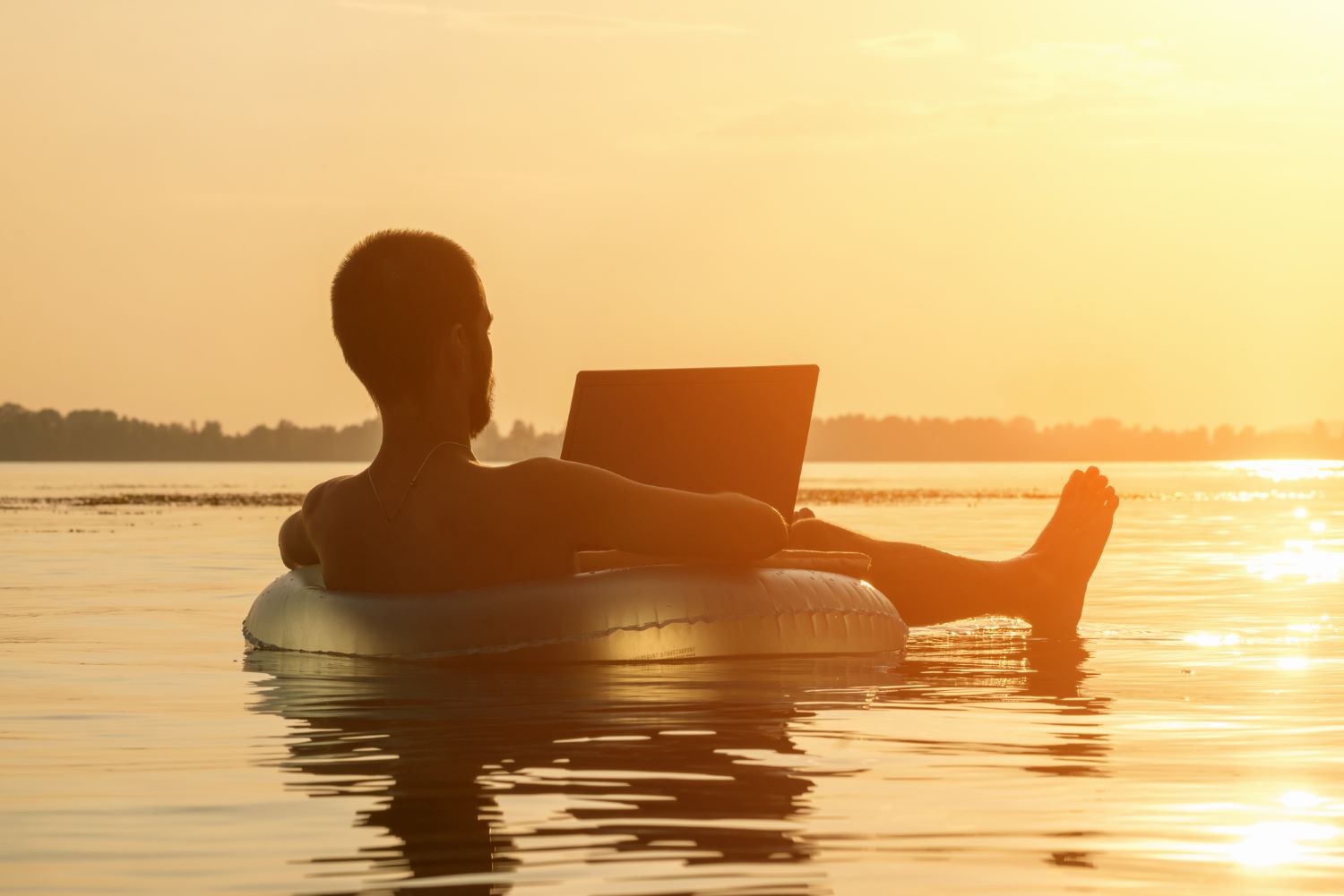 Een man die in het water ligt met zonsondergang.