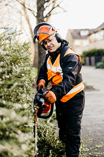 Werken in de groenvoorziening en bezig met het snoeien van een heg.