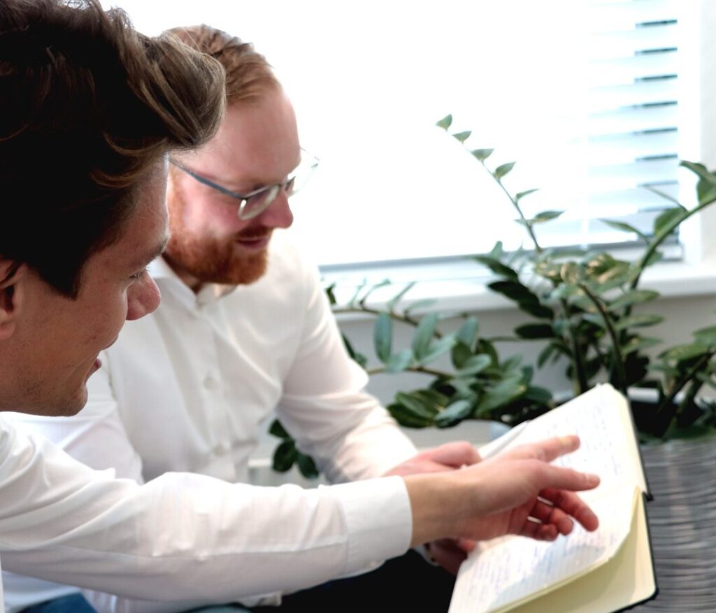 Twee mannen die samen een boek lezen.