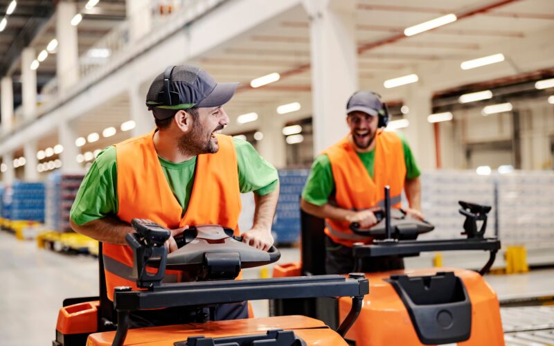 2 mensen zitten op wagentjes in het magazijn te rijden.