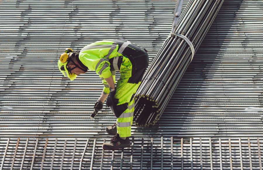 Een medewerker die stalen buizen aan het neerleggen is als voorbereiding van het cement.