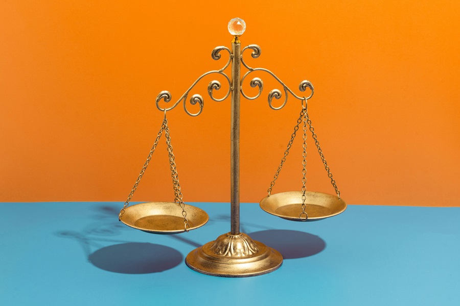 Weegschaal goud met oranje en blauwe achtergrond.