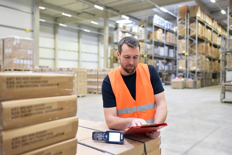 een logistiek medewerker die bezig is met zijn werkzaamheden in een magazijn