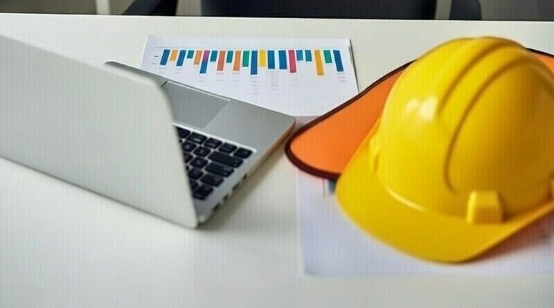 bouwhelm, laptop en papieren met grafieken op tafel