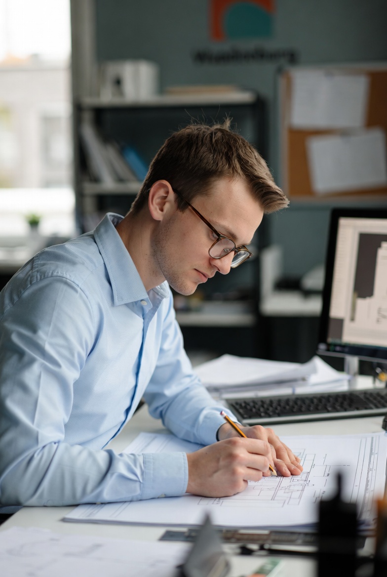 een tekenaar junior die aan het tekenen is achter zn bureau